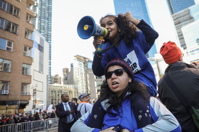 в N.Y.C., a young protestor makes her voice heard via a megaphone. 